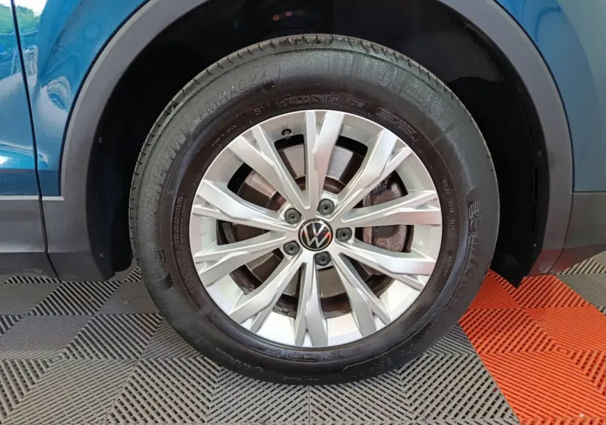 Gros plan sur la roue avant droite du Volkswagen Tiguan bleu 1.4 EHYBRID avec jante alliage à rayons fins.