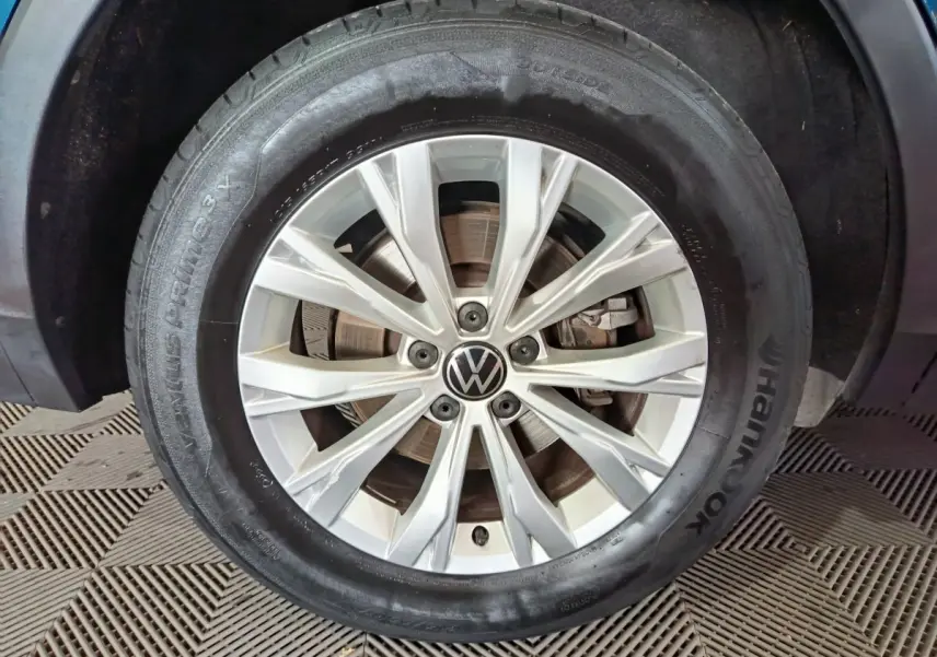 Gros plan sur la jante alliage argentée et pneu Hankook d'un Volkswagen Tiguan bleu hybride rechargeable 2022.
