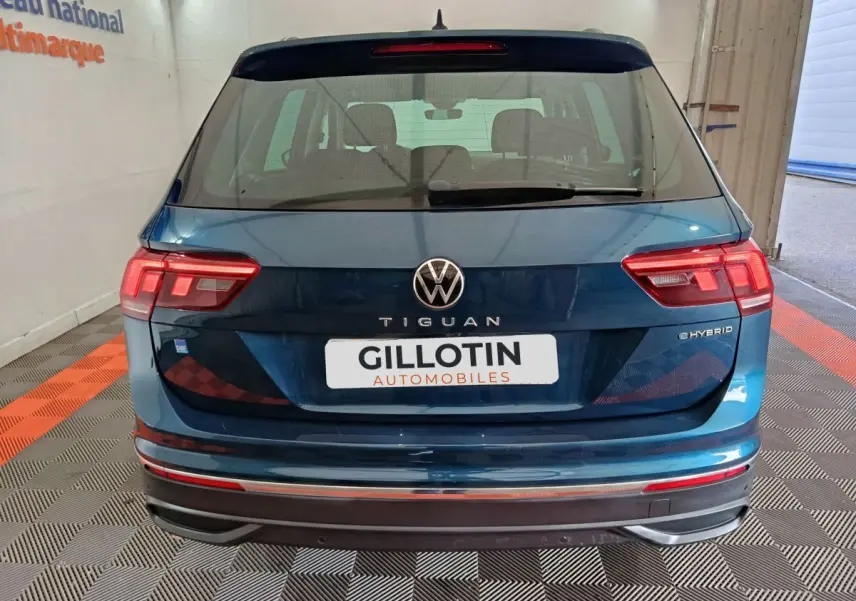 Vue arrière d'un Volkswagen Tiguan bleu hybride rechargeable 2022 avec feux LED et logo eHYBRID visible.