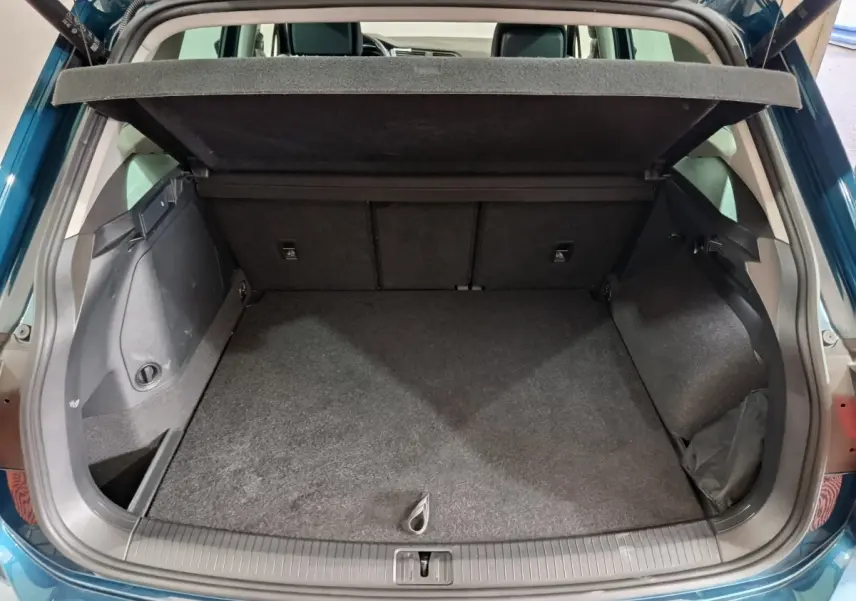 Coffre ouvert vu de l'arrière d'un Volkswagen Tiguan bleu, montrant un espace de chargement propre et spacieux.