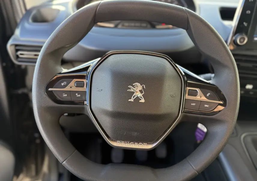 Gros plan sur le volant noir du Peugeot Rifter 2020, avec logo lion et commandes intégrées sur les branches.