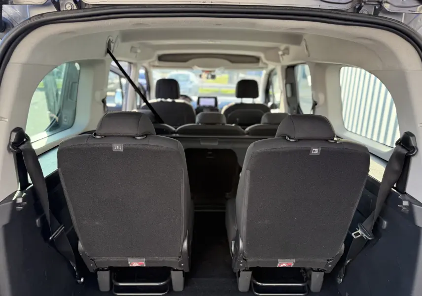 Vue intérieure arrière du Peugeot Rifter gris, montrant les sièges arrière en tissu et l'espace passagers sur 7 places.