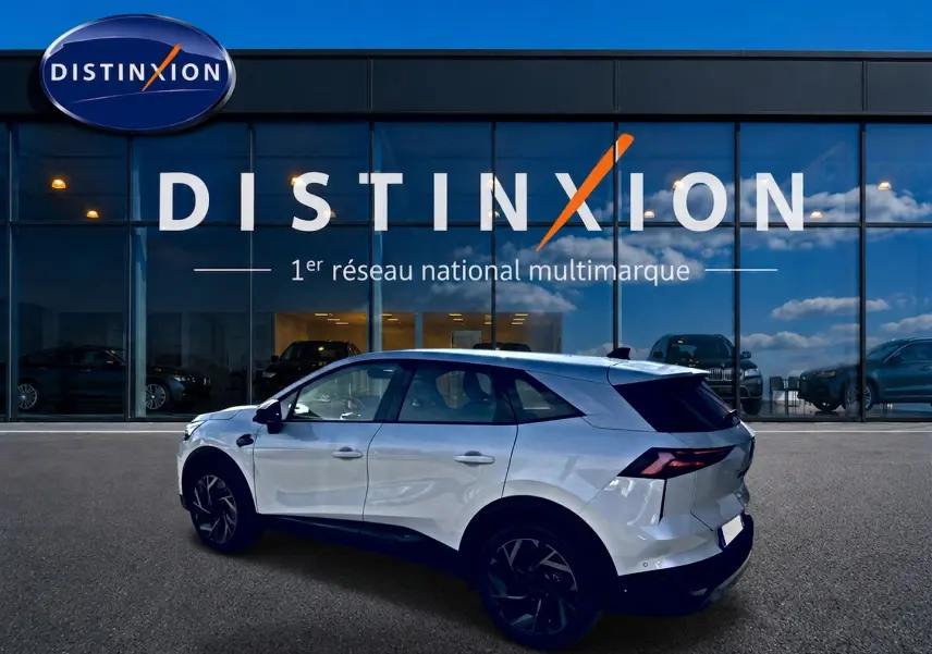 Vue latérale gauche d'un Renault Symbioz blanc nacré avec jantes noires, devant une vitrine Distinxion.
