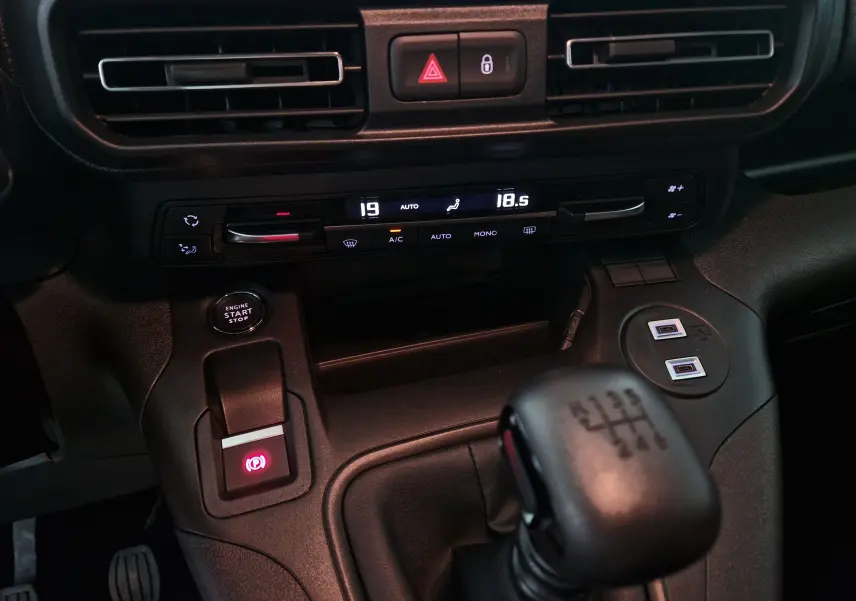 Vue rapprochée de la console centrale de l'Opel Combo Life avec boîte manuelle, climatisation digitale et bouton start/stop.