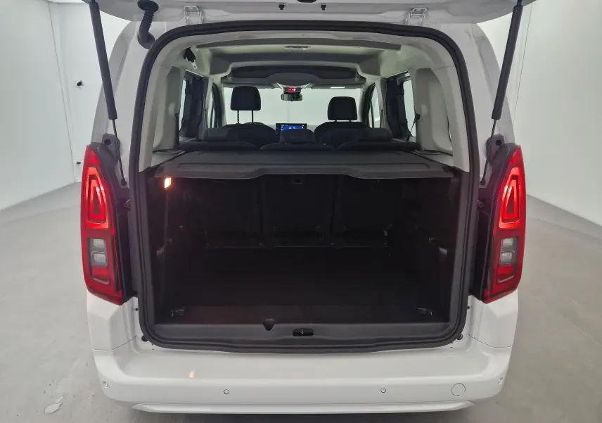Vue arrière d'un Opel Combo Life blanc avec coffre ouvert et banquette arrière visible, intérieur spacieux et lumineux.