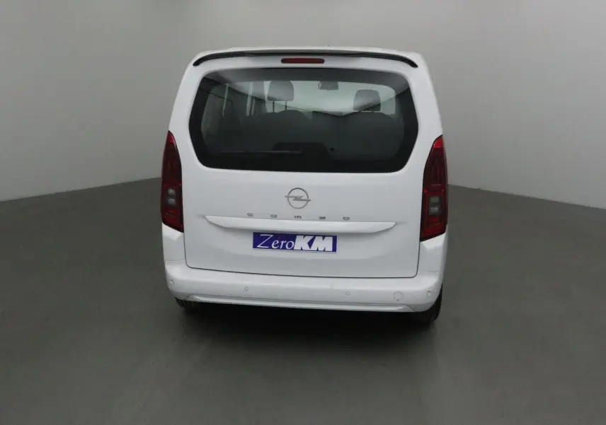 Vue arrière d'un Opel Combo Life blanc avec hayon vitré et becquet arrière dans un studio neutre.