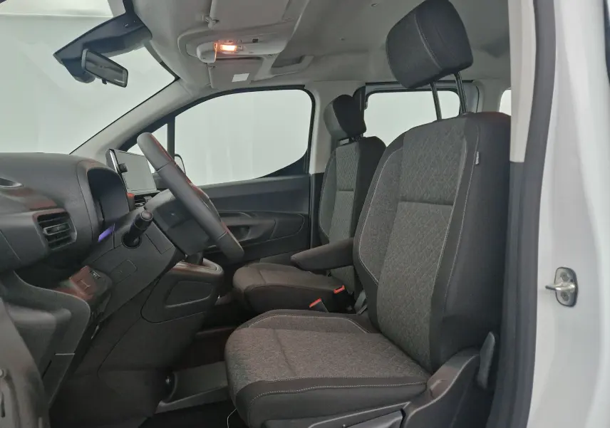 Intérieur avant côté gauche d’un Opel Combo Life blanc, montrant les sièges tissu gris et le tableau de bord épuré.