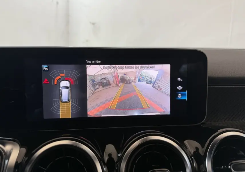 Écran tactile intérieur montrant la caméra de recul et l'aide au stationnement du Mercedes GLB 200 d AMG Line noir.