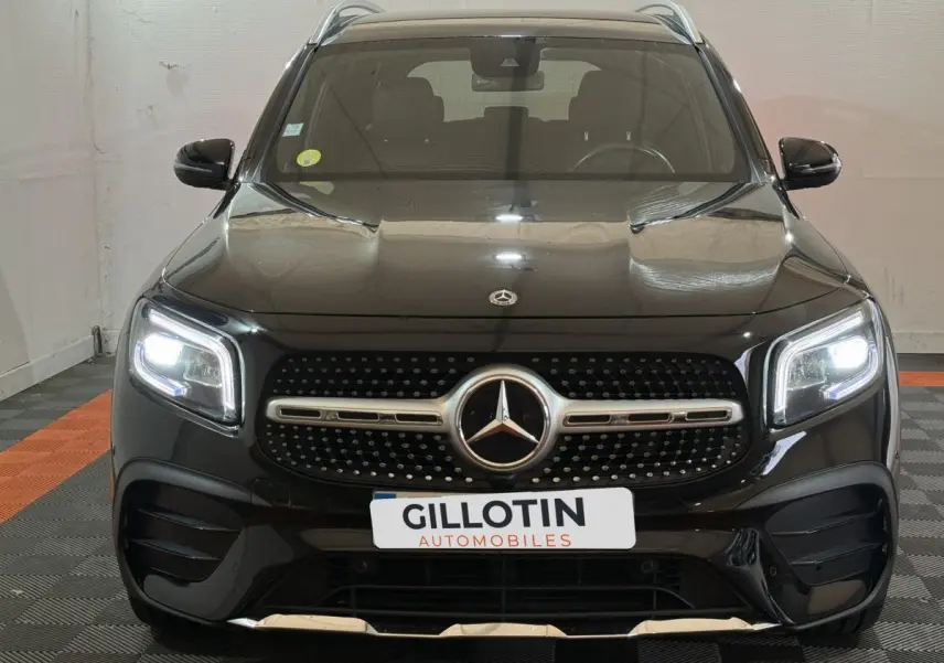 Vue frontale d'un Mercedes GLB 200 d AMG Line noir avec phares LED allumés et calandre distinctive AMG.