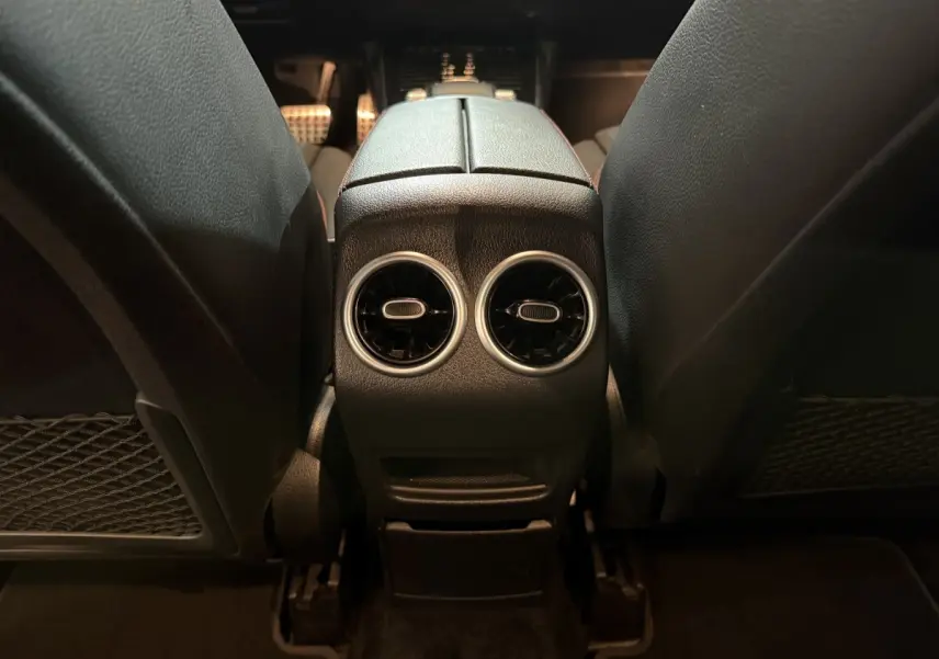 Vue rapprochée de l'espace entre les sièges avant noirs du Mercedes GLB 200 d AMG Line, intérieur sombre.