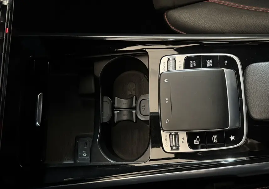 Vue plongeante sur la console centrale noire du Mercedes GLB 200 d AMG Line avec pavé tactile et porte-gobelets.