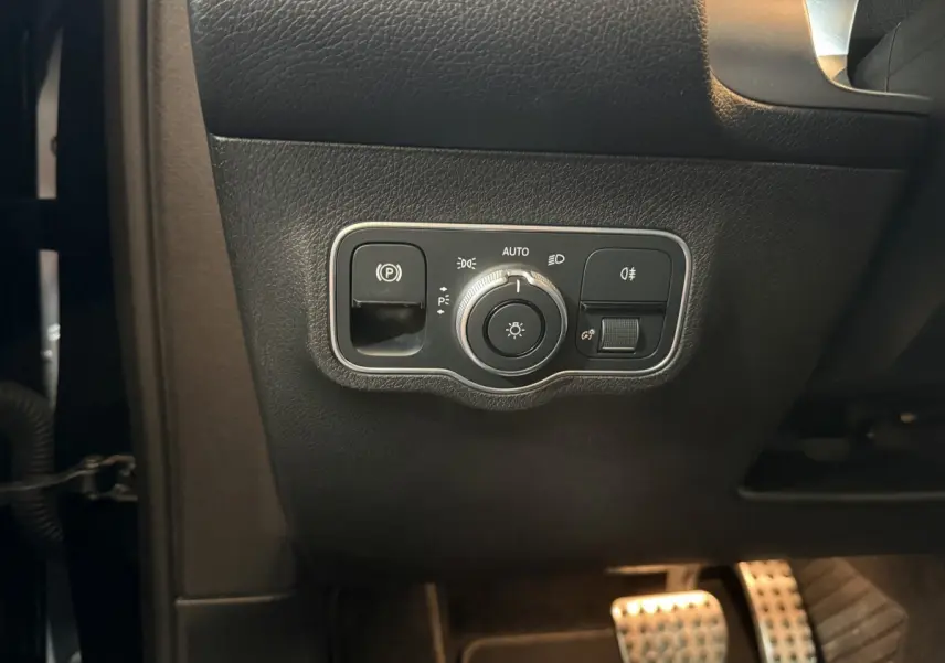 Gros plan sur les commandes d’éclairage et frein à main électrique côté gauche du tableau de bord noir du Mercedes GLB 200 d AMG Line 2020.