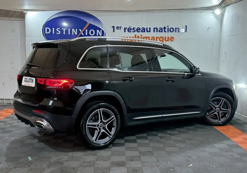 Mercedes GLB 200 d AMG Line noir vue de profil côté droit, avec jantes alliage et feux arrière allumés dans un showroom.