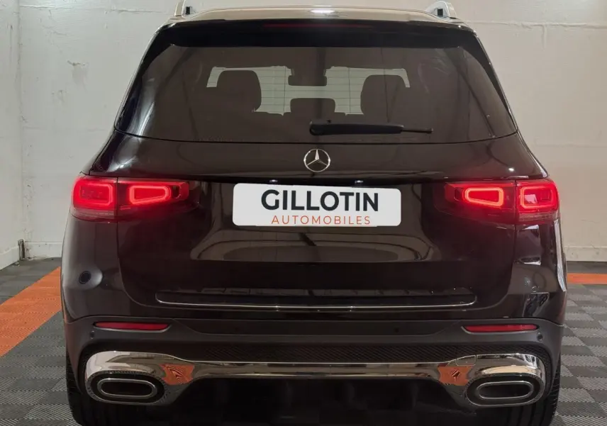 Vue arrière d'un Mercedes GLB 200 d AMG Line noir avec feux LED allumés et double sortie d'échappement chromée.