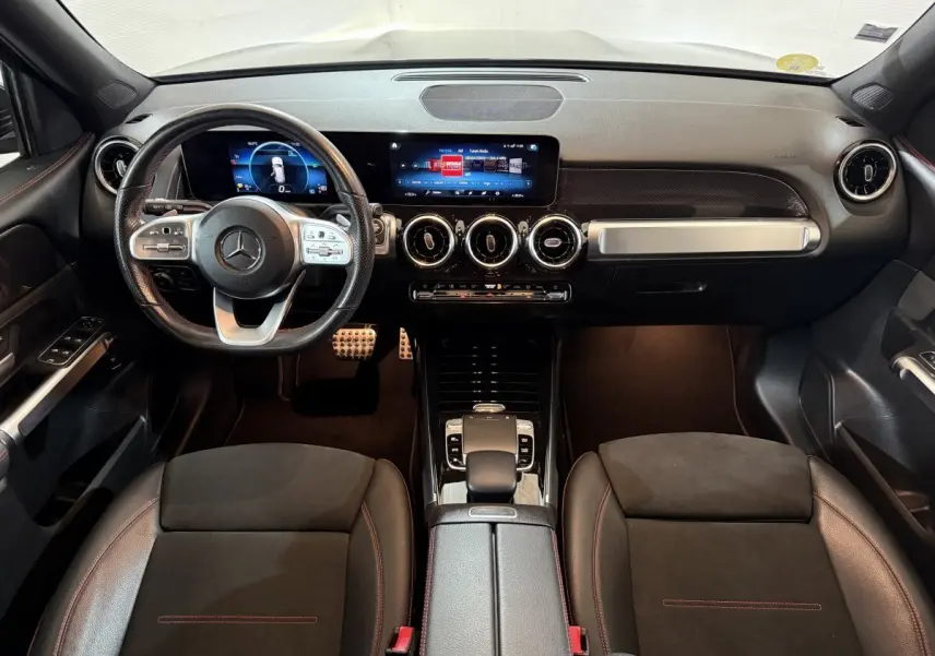 Vue intérieure frontale du tableau de bord et volant cuir noir du Mercedes GLB 200 d AMG Line avec écrans digitaux.