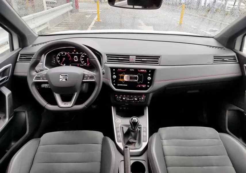 Vue intérieure avant du SEAT Arona 2020, tableau de bord noir avec volant multifonction et boîte manuelle.