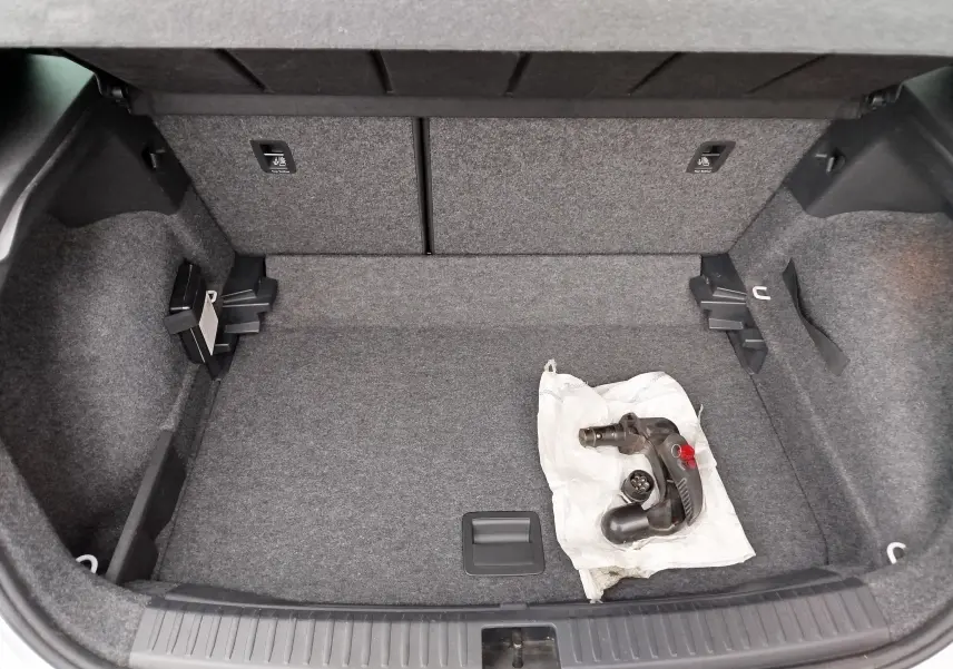 Coffre ouvert d'un SEAT Arona blanc avec toit gris, vue plongeante sur l'espace de chargement et un attelage posé.