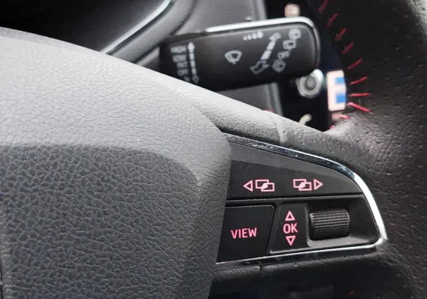 Gros plan sur les commandes au volant noir avec surpiqûres rouges du SEAT Arona blanc, version FR 2020.