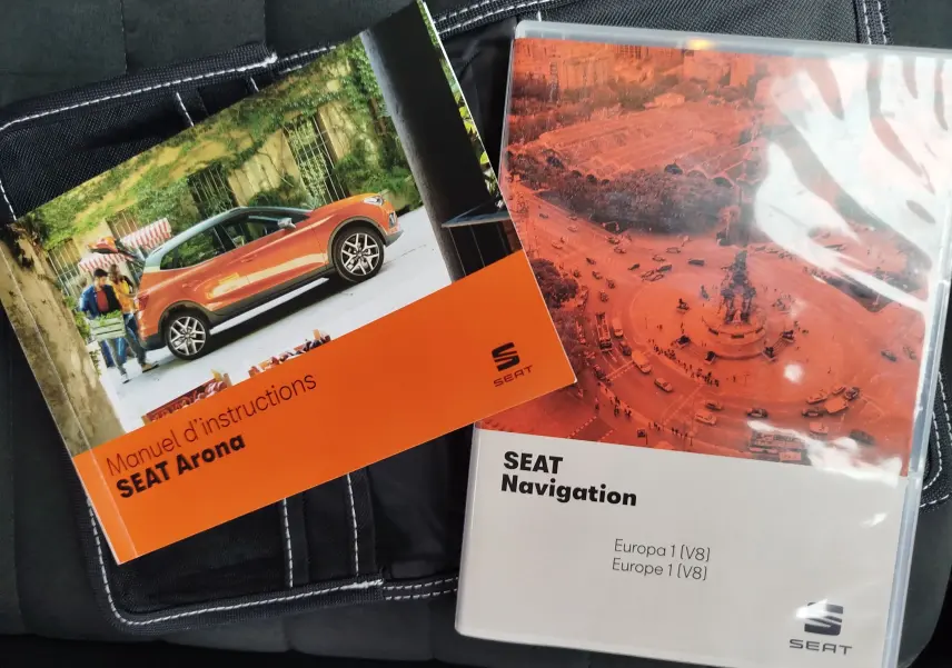 Vue de profil gauche d'un SEAT Arona blanc avec toit gris magnétique, illustré sur la couverture d'un manuel d'instructions.