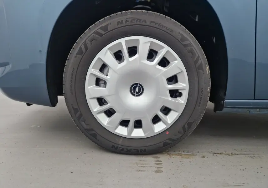 Gros plan sur la roue avant gauche bleu Kiama de l'Opel Combo Life 2025 avec enjoliveur argenté au design moderne.