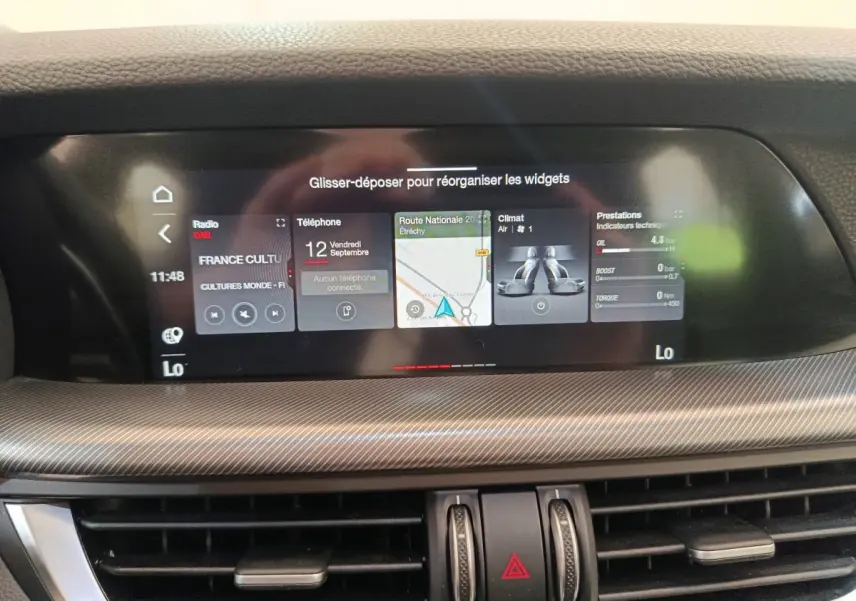 Écran tactile central du tableau de bord de l'Alfa Romeo Stelvio gris foncé, affichant navigation et fonctions connectées.