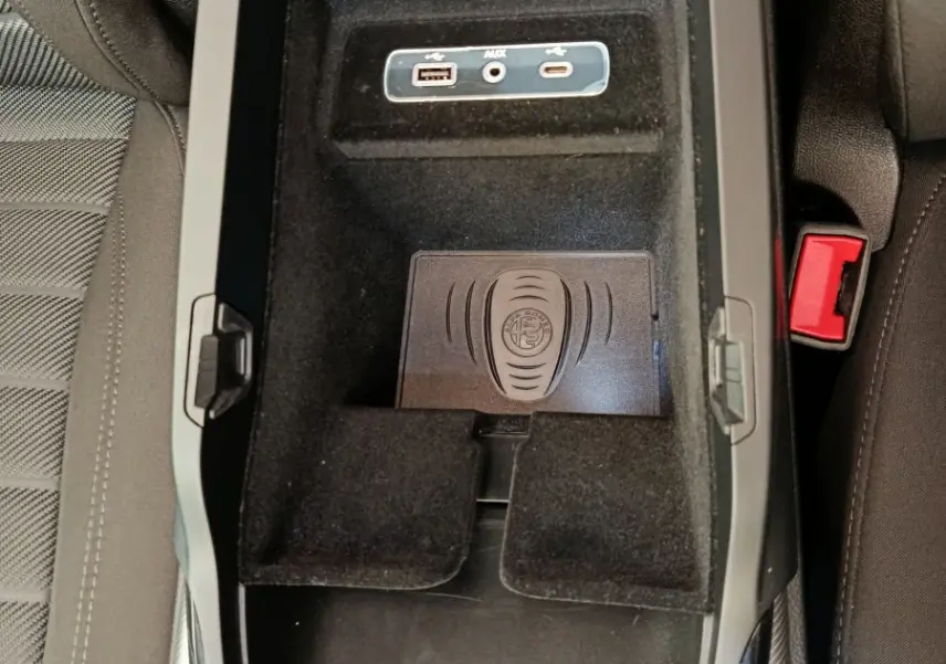 Vue plongeante sur la console centrale noire de l'Alfa Romeo Stelvio gris foncé, avec ports USB et tapis de recharge à induction.