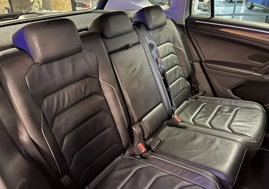 Vue intérieure des sièges arrière en cuir noir du Volkswagen Tiguan 2.0 TDI 150 Carat, avec accoudoir central relevé.