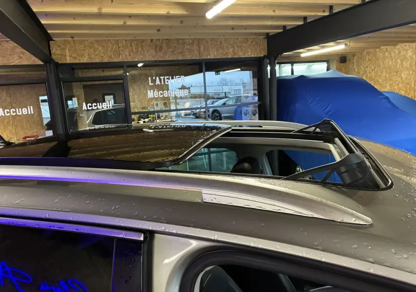 Toit ouvrant ouvert vu de dessus sur un Volkswagen Tiguan gris 2017 dans un garage.