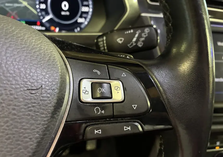 Gros plan sur les commandes multifonctions à droite du volant noir du Volkswagen Tiguan 2.0 TDI 150 Carat 2017.