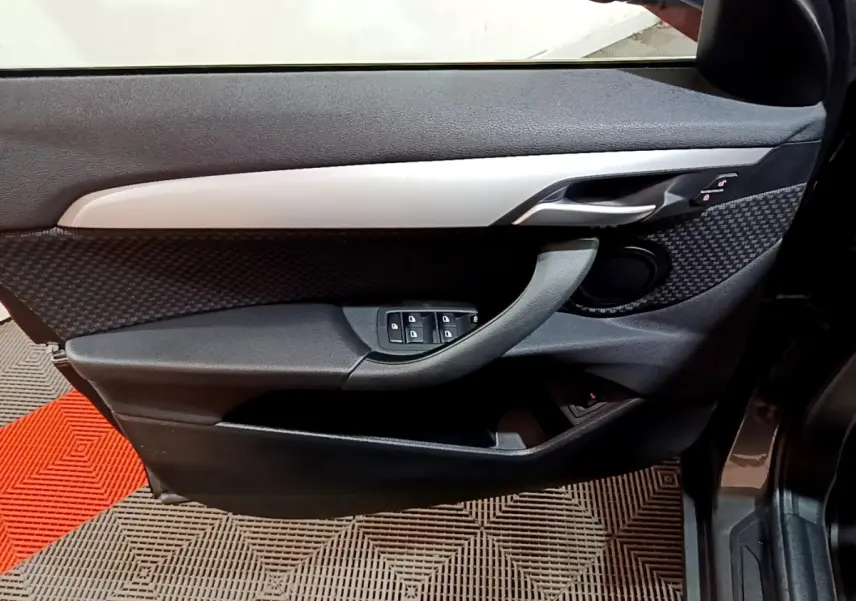 Vue intérieure du panneau de porte avant gauche gris foncé de la BMW X2 sDrive18i Lounge DKG7 2021 avec commandes électriques.