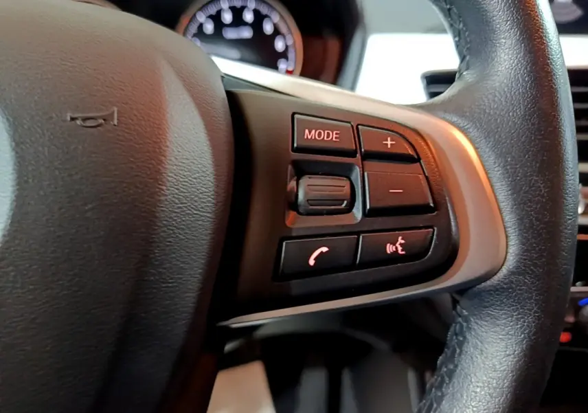 Gros plan sur les commandes multimédias au volant cuir noir du BMW X2 sDrive18i Lounge 2021.