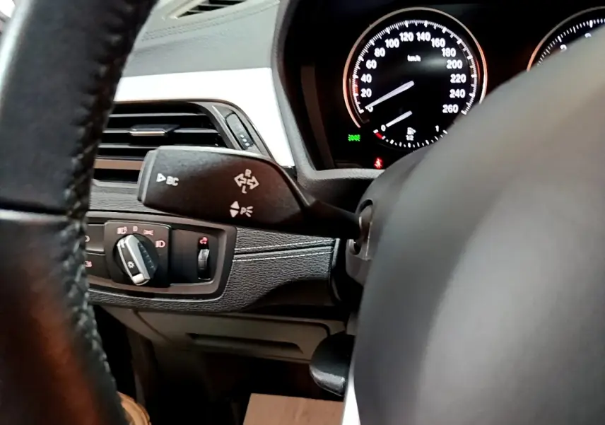 Gros plan sur le volant cuir et le combiné d'instruments lumineux du tableau de bord d'une BMW X2 2021 gris foncé.