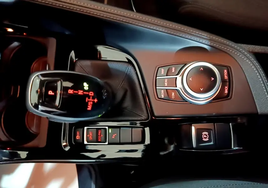 Vue rapprochée de la console centrale noire de la BMW X2 sDrive18i Lounge DKG7 avec levier de vitesse automatique et molette de commande.