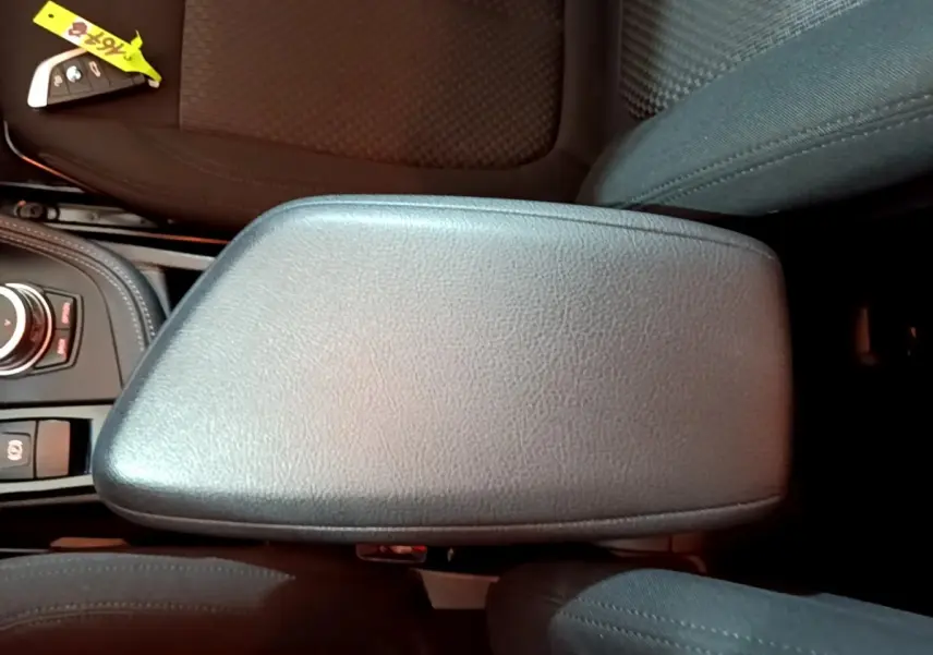 Vue rapprochée de l'accoudoir central en cuir noir et de la clé BMW sur le siège avant d'un BMW X2 gris foncé.