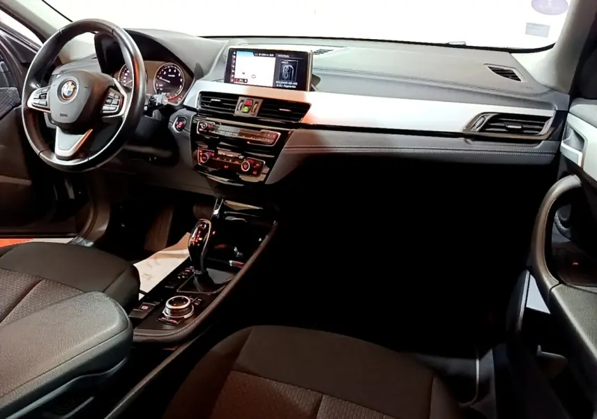 Vue intérieure de face droite du tableau de bord noir et gris avec écran central et volant cuir de la BMW X2 sDrive18i Lounge DKG7.