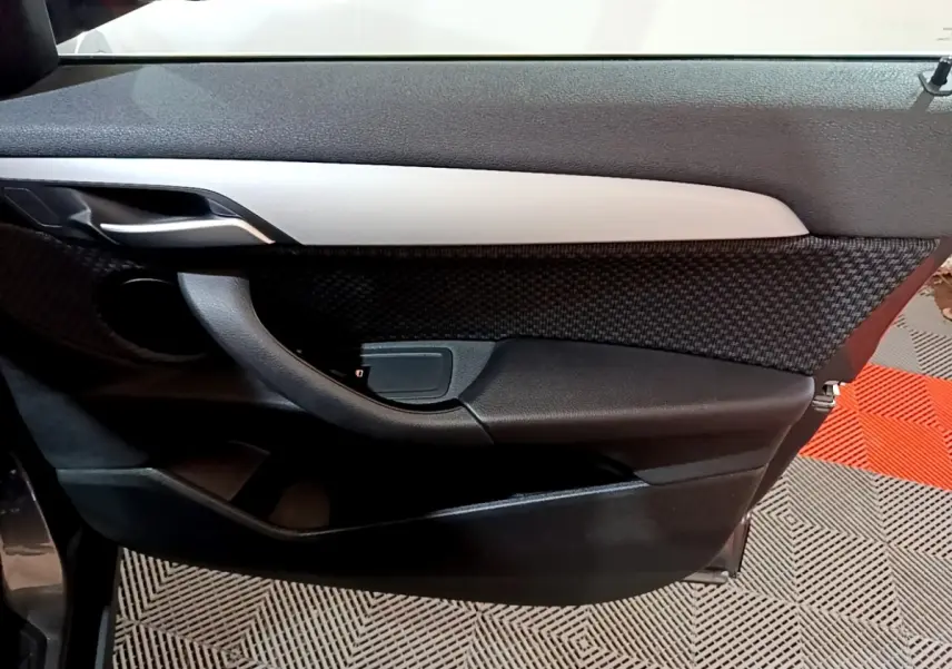 Gros plan sur la porte intérieure côté gauche de la BMW X2 sDrive18i Lounge 2021 avec insert gris et tissu texturé.