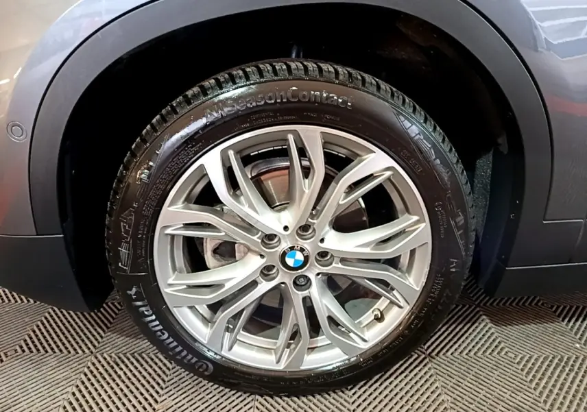 Gros plan sur la roue avant droite avec jante argentée du BMW X2 gris foncé sDrive18i Lounge 2021.