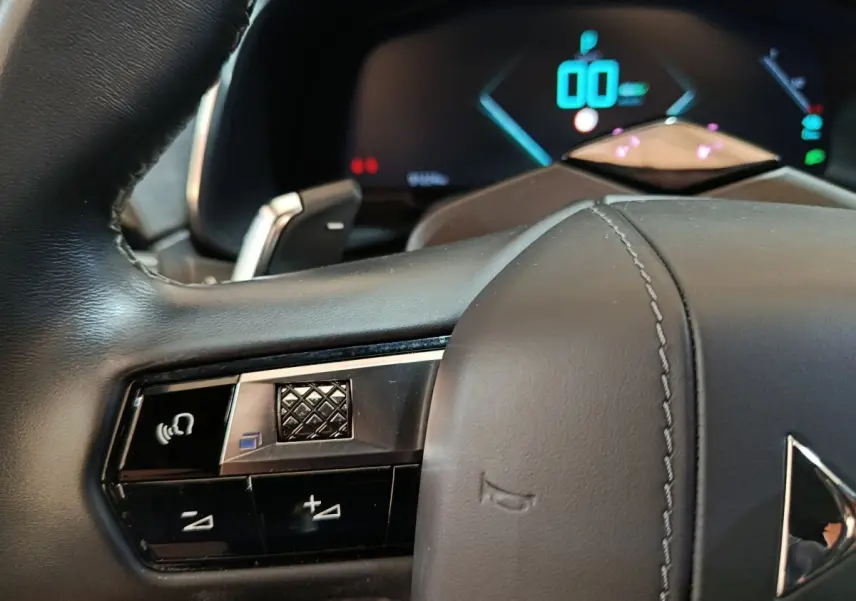 Gros plan sur la partie gauche du volant cuir noir du DS7 Crossback E-TENSE avec commandes vocales et tableau de bord numérique.
