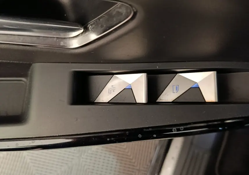 Gros plan sur les boutons de réglage des rétroviseurs argentés et noirs dans l'habitacle du DS7 Crossback noir.