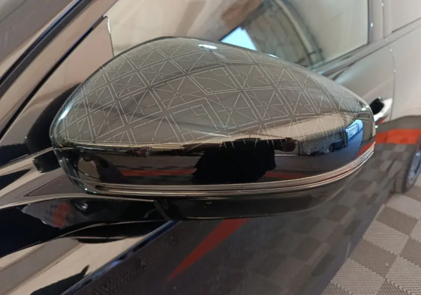 Rétroviseur côté gauche noir brillant du DS7 Crossback E-TENSE 4x4 300 LOUVRE avec motif géométrique gravé.