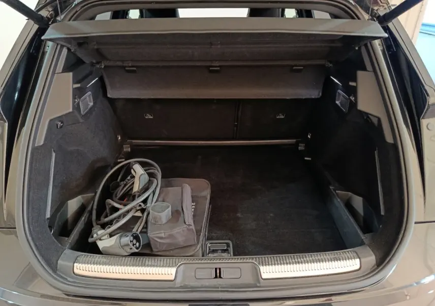 Vue arrière du coffre noir du DS7 Crossback E-TENSE 4x4 300 Louvre avec câble de recharge hybride visible.