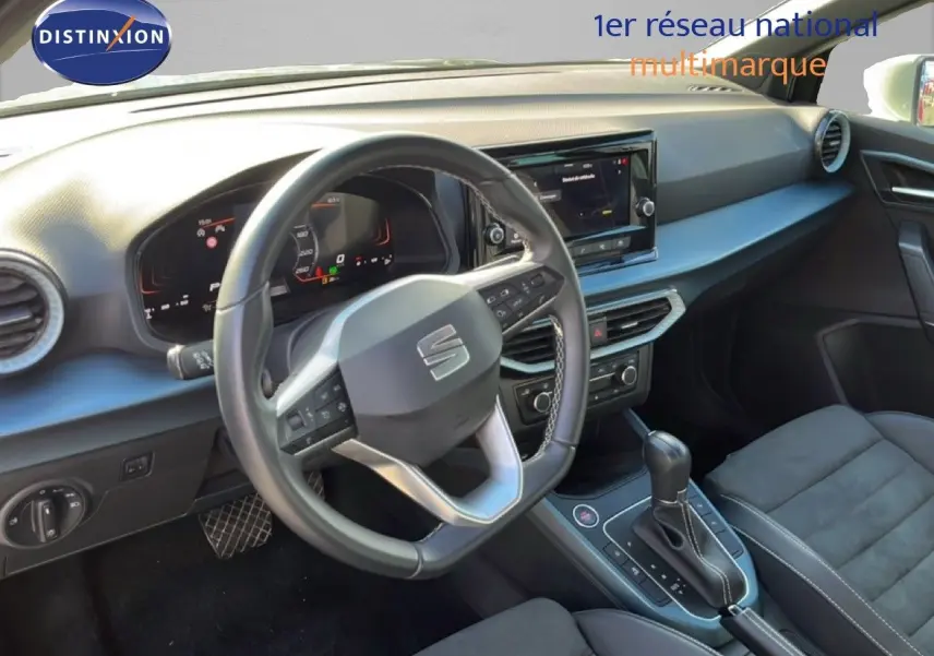 Vue intérieure du poste de conduite du SEAT Arona 2025, volant multifonction et console centrale avec boîte automatique.