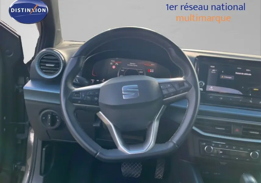 Vue intérieure centrée sur le volant cuir multifonction d'une SEAT Arona 2025, avec tableau de bord digital et écran tactile.