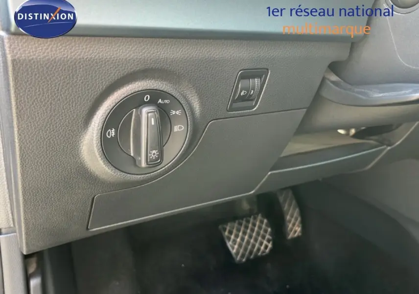 Gros plan sur le tableau de bord côté gauche du SEAT Arona 2025, montrant la commande des phares et les pédales.