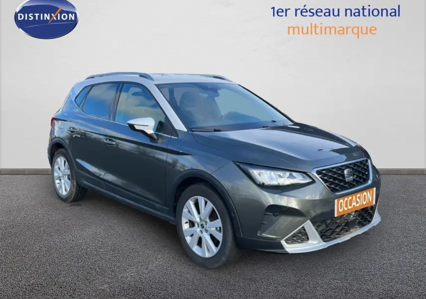 SEAT Arona gris magnétique métal vue 3/4 avant droit avec toit noir et jantes argentées, en extérieur sur sol goudronné.