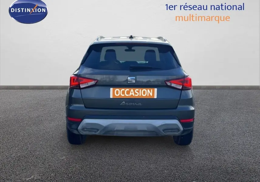 Vue arrière d'un SEAT Arona gris magnétique métal avec toit blanc, mettant en valeur ses feux arrière anguleux et son pare-chocs contrasté.