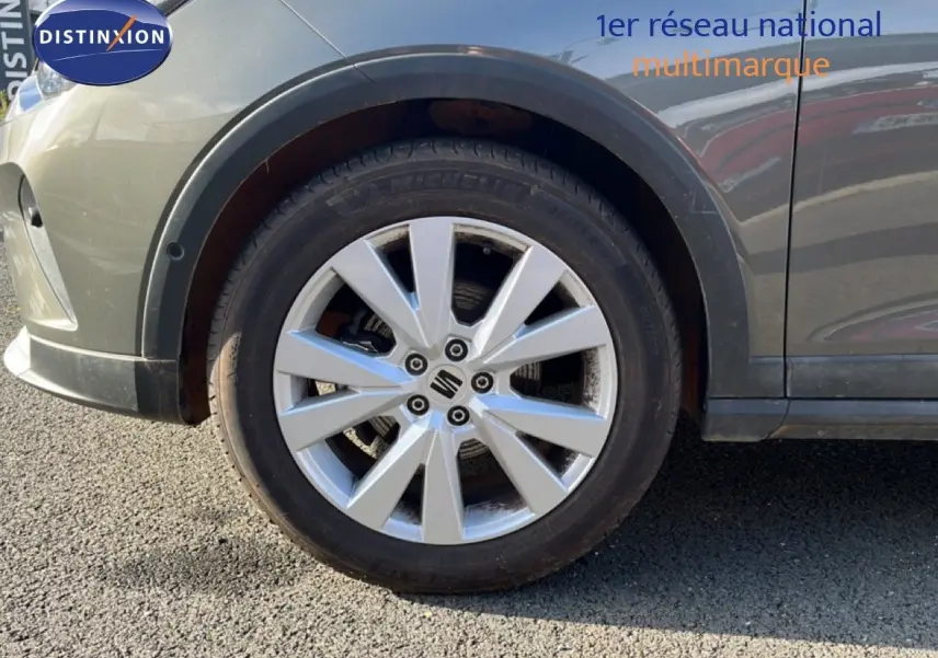 Gros plan sur la roue avant gauche d’un SEAT Arona gris magnétique avec jante alliage et logo central visible.