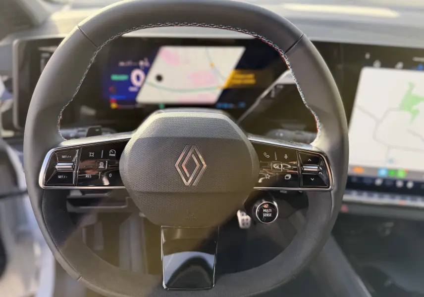 Vue rapprochée du volant cuir du Renault Austral 2025 avec commandes intégrées et écran numérique en arrière-plan.