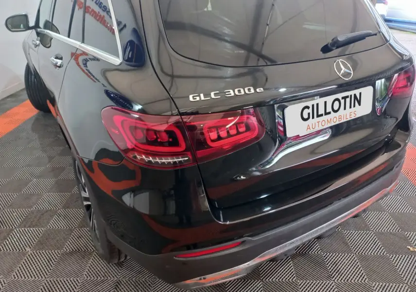 Vue 3/4 arrière gauche d'un Mercedes GLC 300e noir brillant avec feux arrière LED et logo sur coffre.
