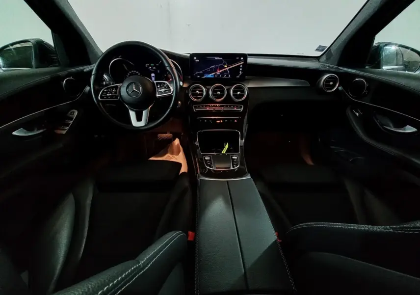 Vue intérieure avant du Mercedes GLC 300 E Business Line 2021, tableau de bord noir avec écran tactile et volant cuir.